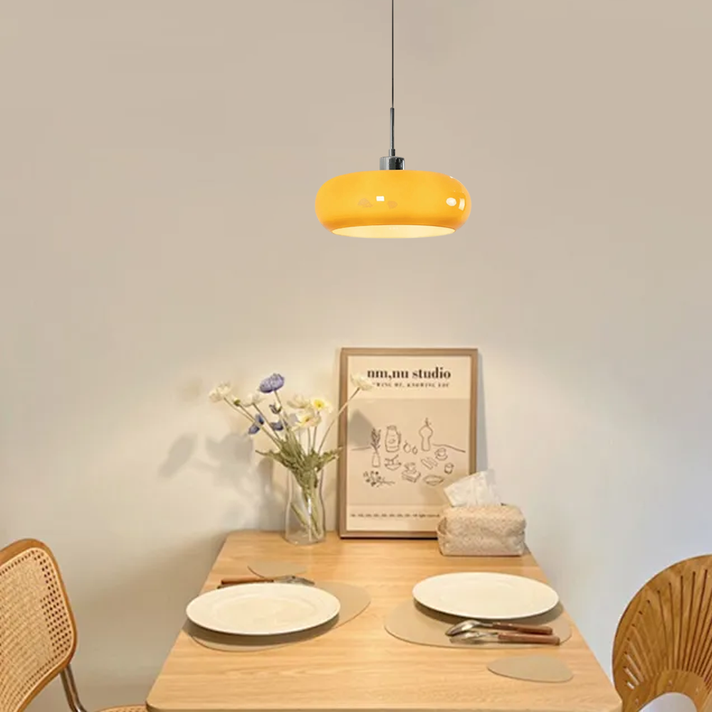 Moderne LED-Pendelleuchte aus orangefarbenem Glas über einem Esstisch im minimalistischen Esszimmer