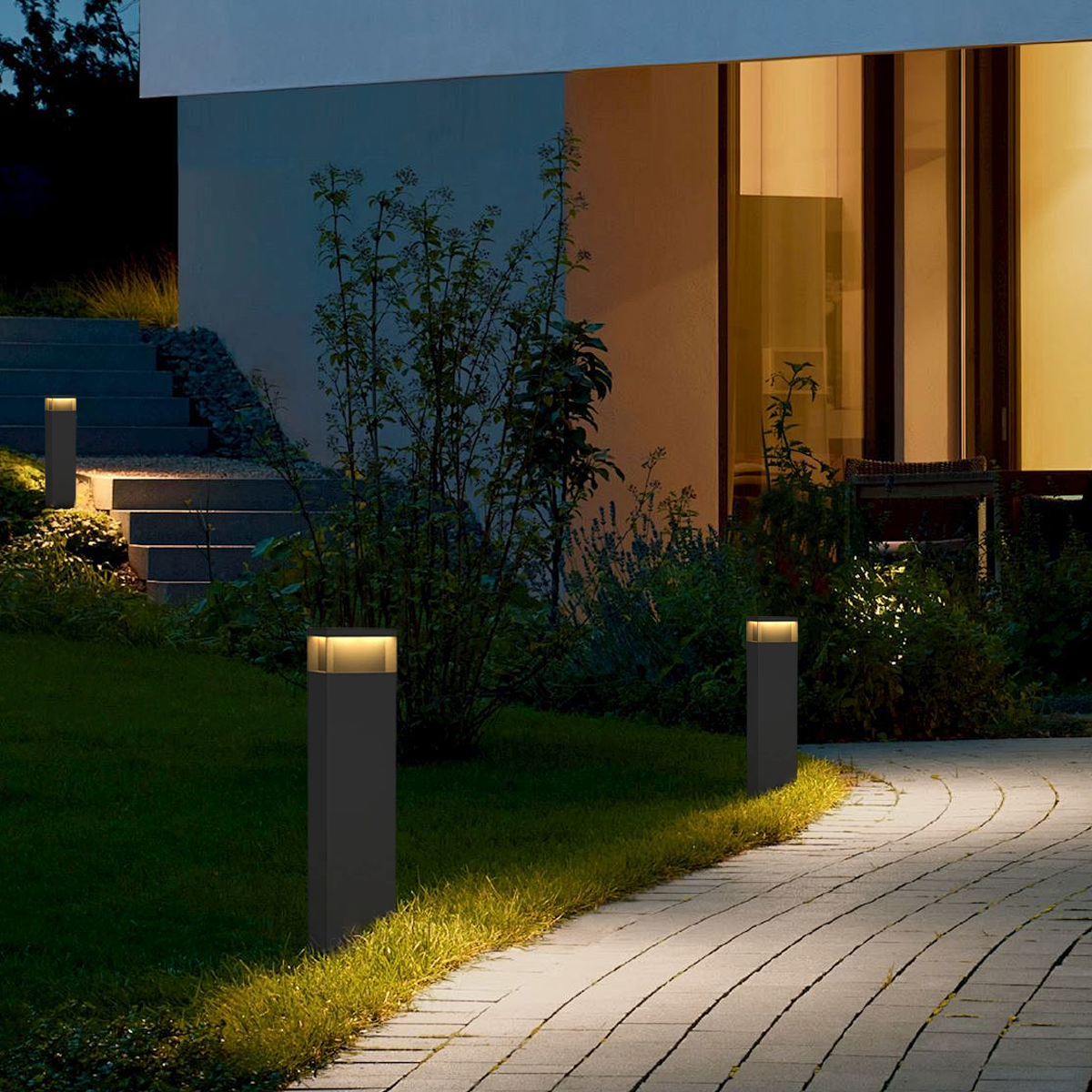 Rechteckige schwarze LED-Solarleuchte aus Metall am Gartenweg bei Dämmerung